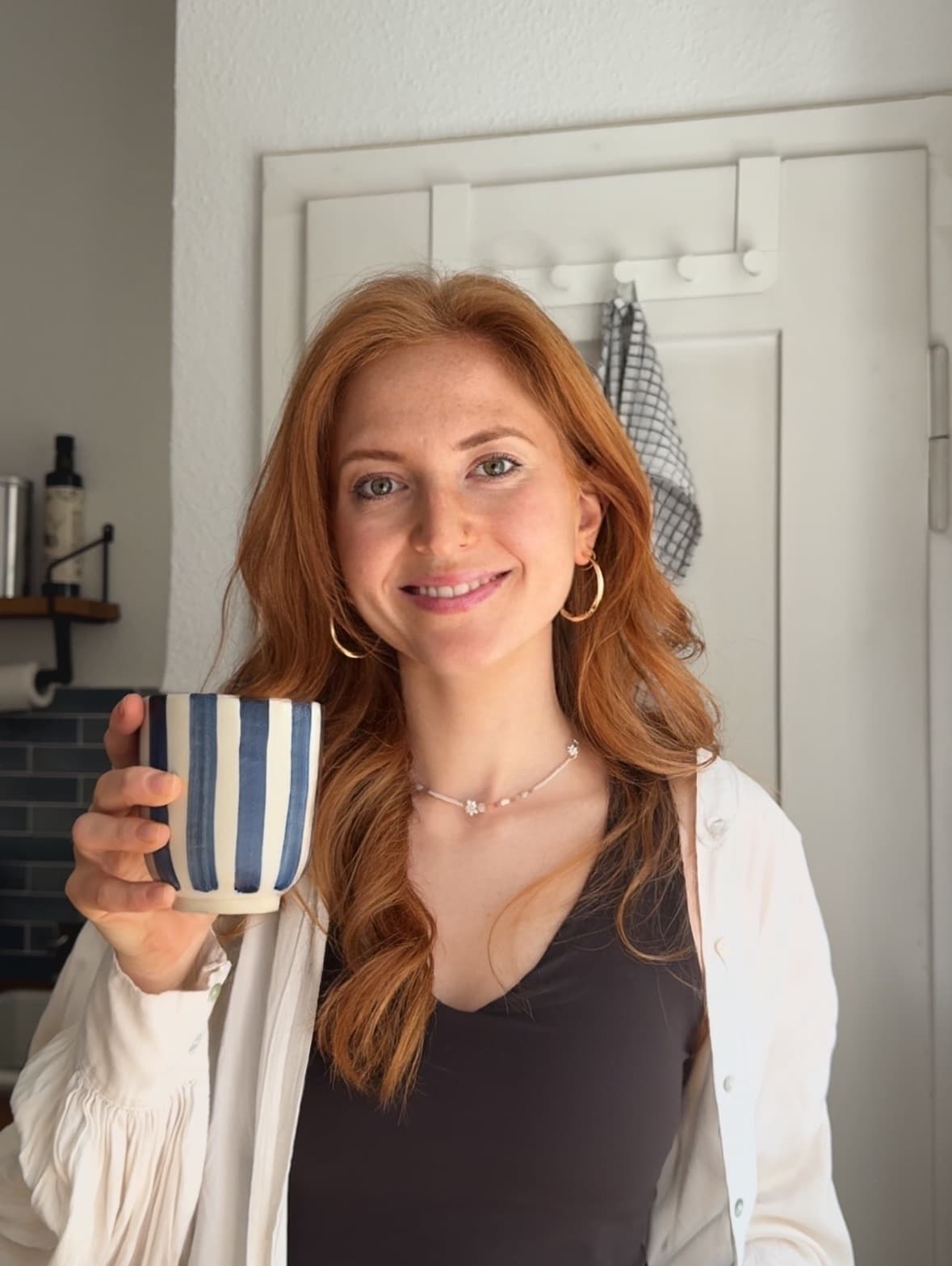 Teresa, co-founder of FoodQuest, holding a striped coffee mug
